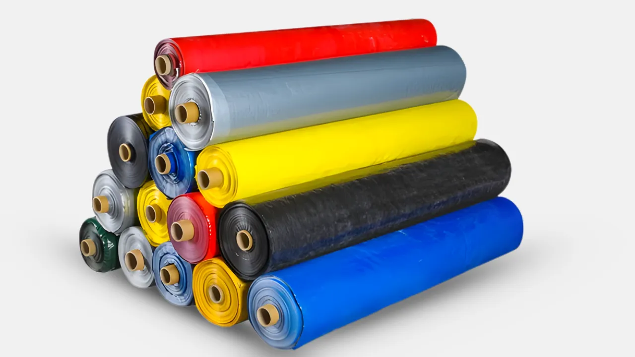 Stack of multicolored HDPE tarpaulin rolls manufactured by trusted tarpaulin supplier in India, offering lightweight, waterproof, and UV-stabilized tarps for agriculture, transport, and construction industries