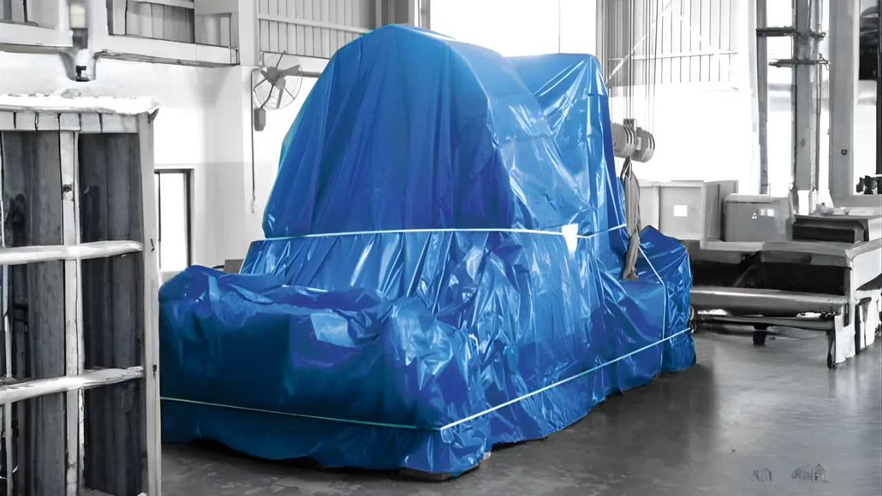 Large blue industrial tarpaulin covering machinery inside a factory, manufactured by leading tarpaulin supplier in India, offering heat, rain, and wind-resistant protection for industrial equipment