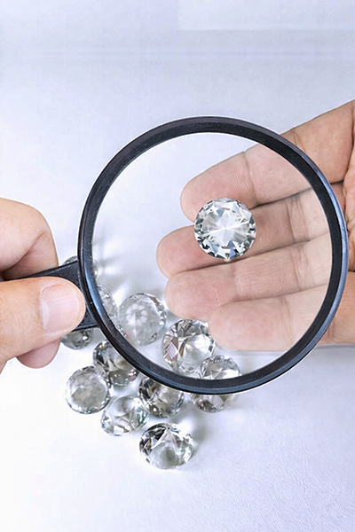 Lab-grown diamond manufacturers inspecting lab grown diamonds with magnifier to ensure trusted quality, clarity, and certification standards in diamond manufacturing process